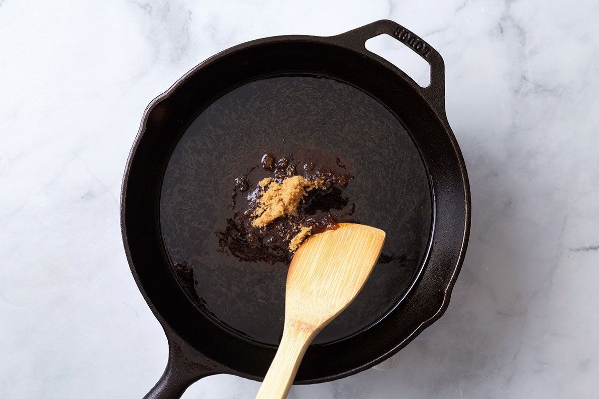 Balsamic vinegar added to a cast iron skillet with brown sugar for making the glaze for step three of Balsamic Pork Tenderloin recipe for Taste of Home
