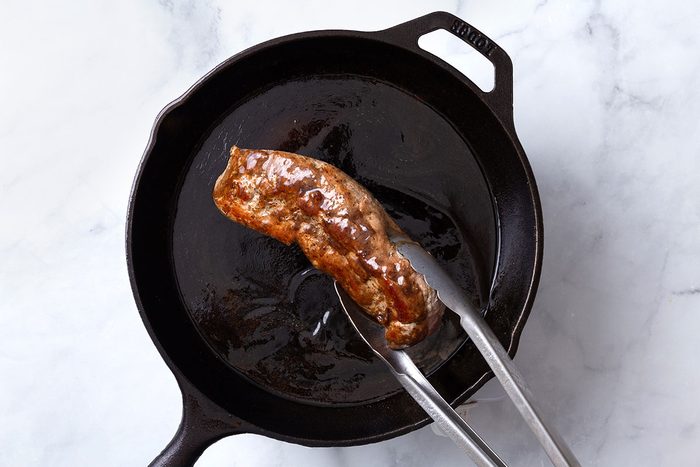 Pork tenderloin being coated in balsamic glaze for step four of Balsamic Pork Tenderloin recipe for Taste of Home