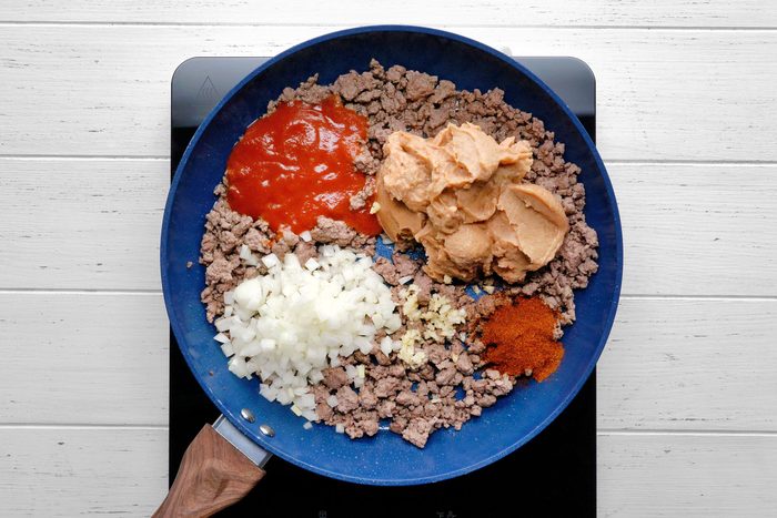 Beans, onion, 1/2 cup tomato sauce, chili powder, garlic and cumin with beef in a skillet.