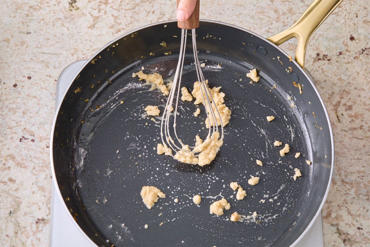 Close shot of add butter to the same skillet over medium heat; whisk tool; marble surface;