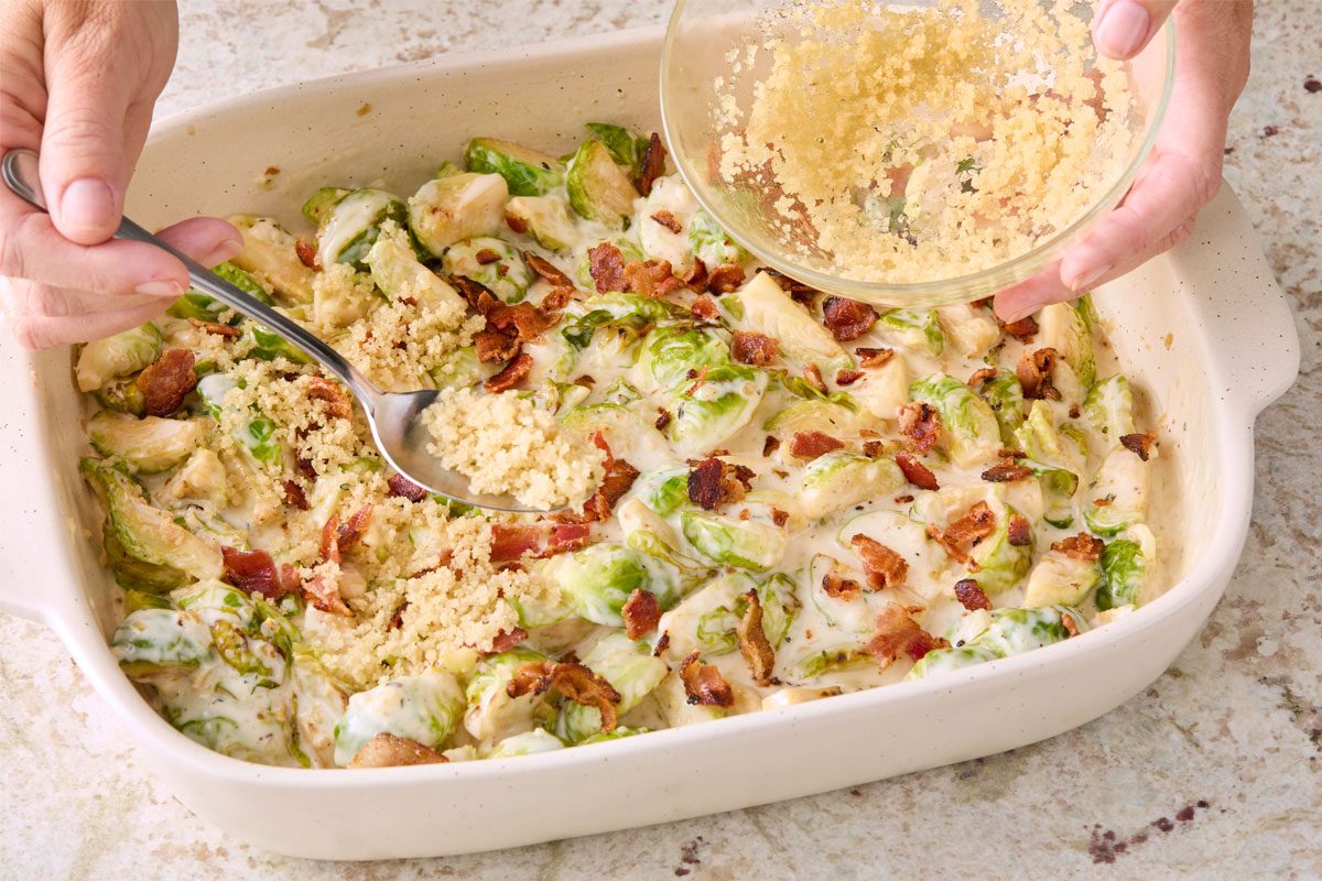 3/4 angle view shot of a small bowl; stir together breadcrumbs and olive oil; sprinkle mixture on top of Brussels sprouts; bake until breadcrumbs are golden brown and sauce is bubbly; 20-23 minutes; spoon; marble surface;