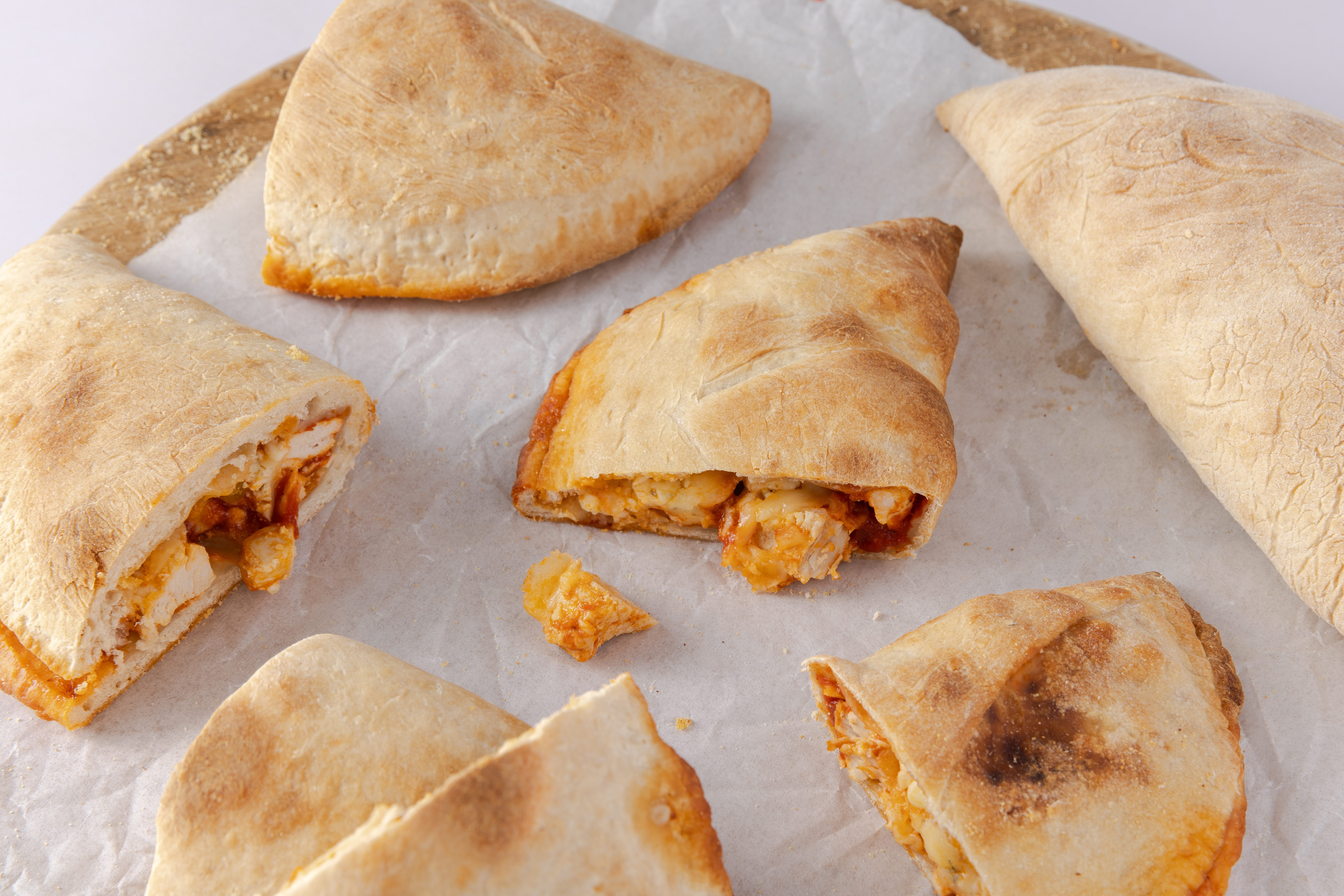 Calzones baked and cut in half on wood board.