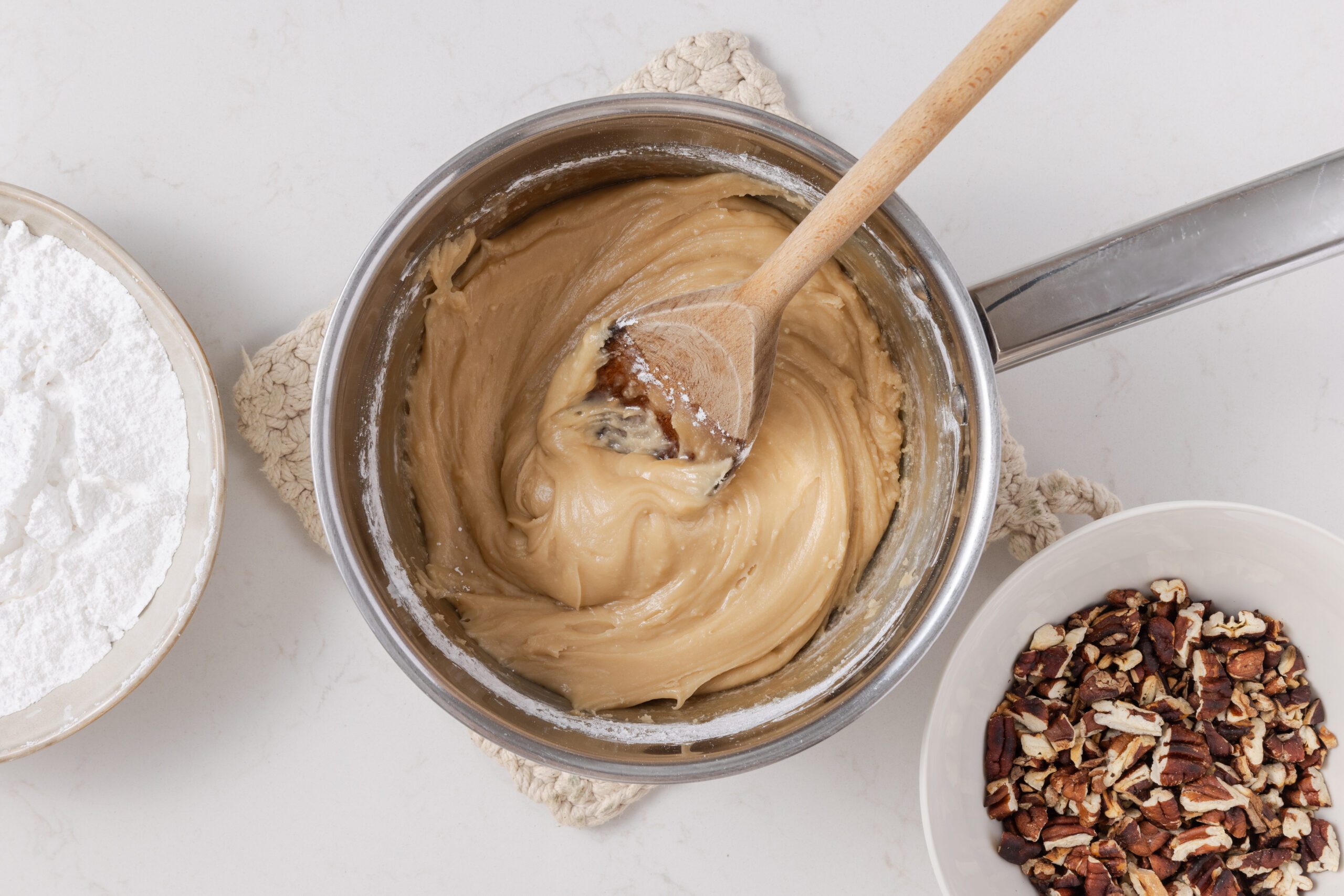 Fudge base cooled down and being beaten with spoon, while mixing confectioner's sugar.