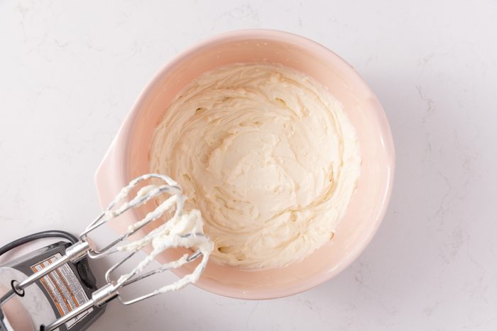 Cannoli cake frosting being prepared in mixing bowl.