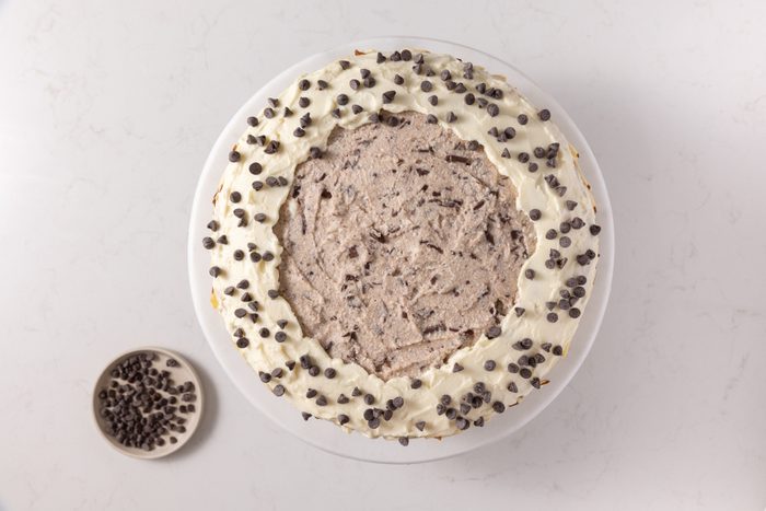 Cake being finalized with sliced almonds and mini chocolate chips.