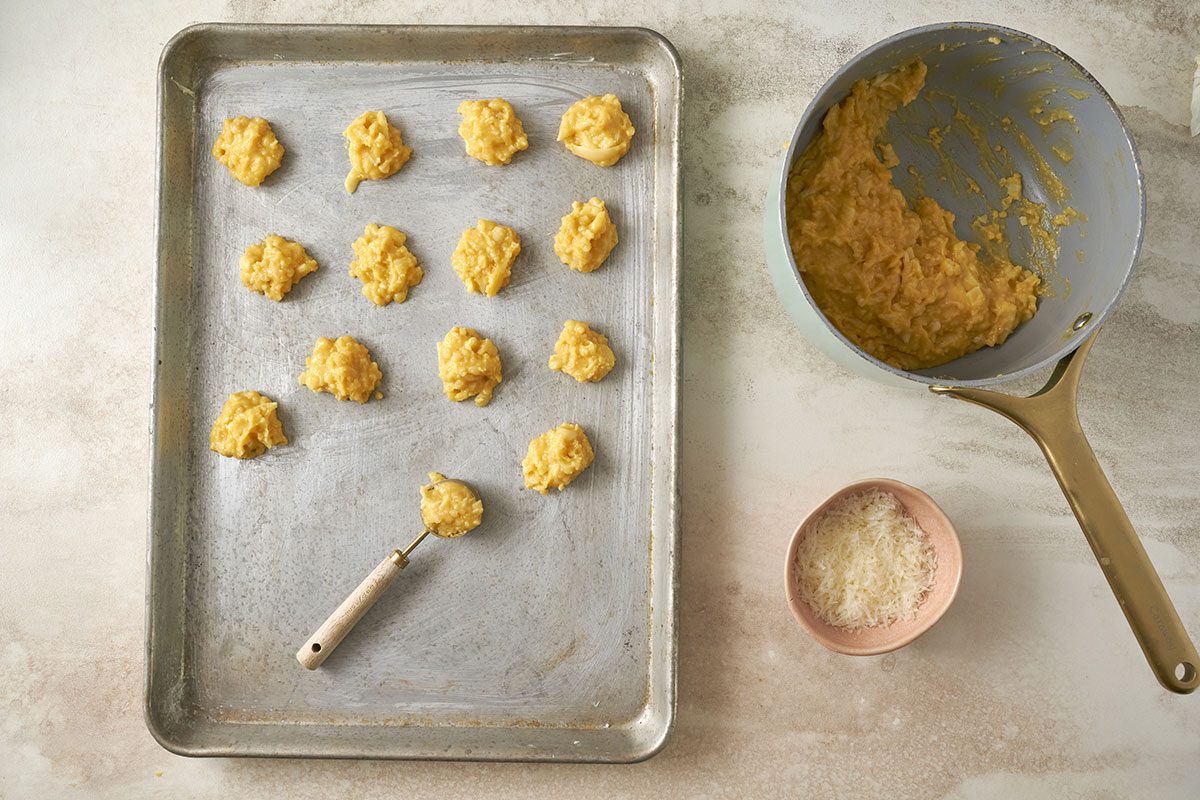 Dropping the dough by 1-inch balls onto a baking sheet and sprinkling with Parmesan cheese for the Cheese Puffs recipe, by Taste of Home.