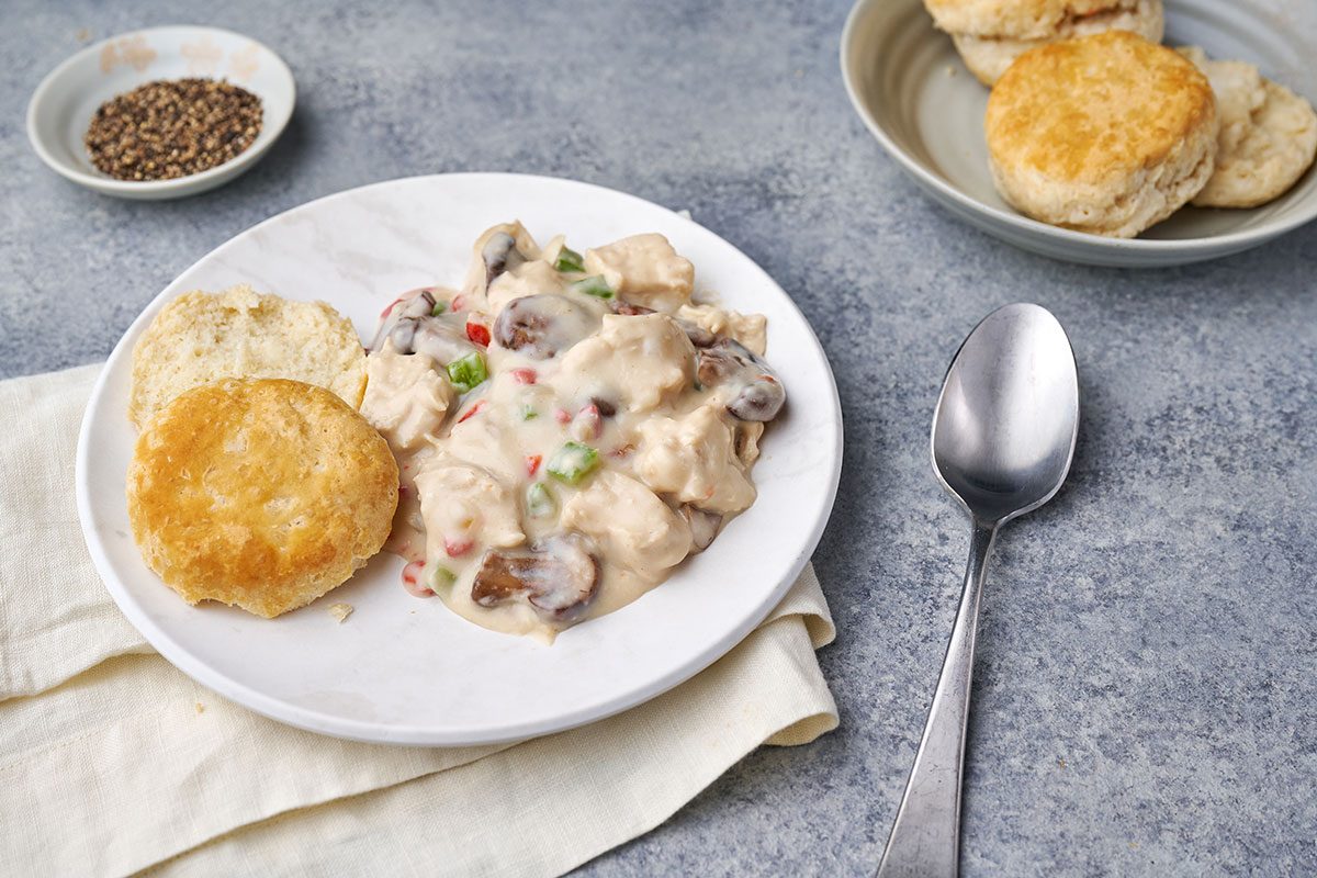 A close-up shot of Chicken à la King, highlighting the tender chicken, pimientos, and rich creamy sauce served on biscuits.