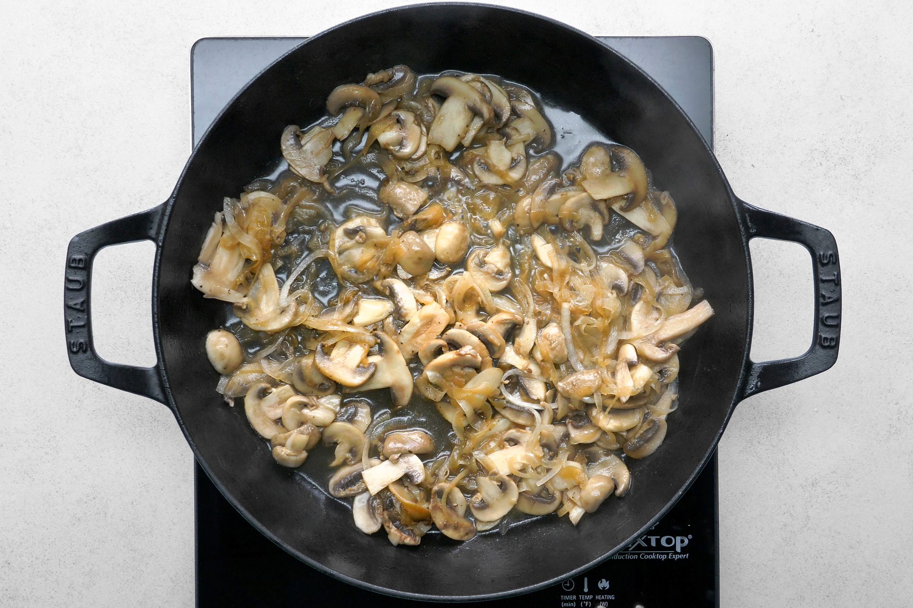 In a pan, butter is being heated over medium-high heat, where mushrooms and onions are sautéed until tender.