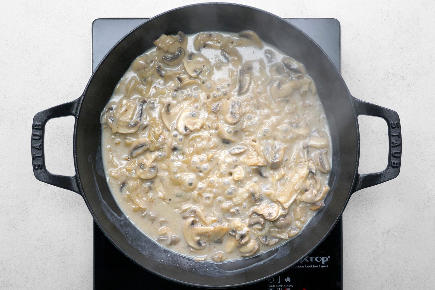 The cornstarch mixture is being stirred and added to the pan, ready to combine with the sautéed mushrooms and onions.