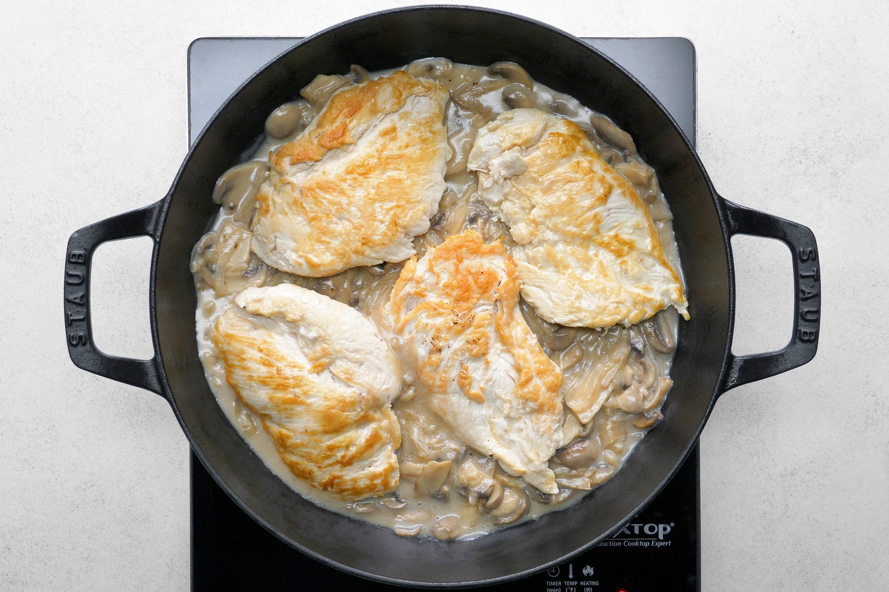 The chicken is being returned to the pan to heat through, allowing it to absorb the flavors of the mushroom sauce.