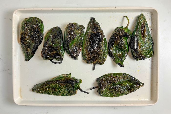 Blistered poblano peppers for Taste of Home Chili Stuffed Poblano Peppers on a white baking sheet