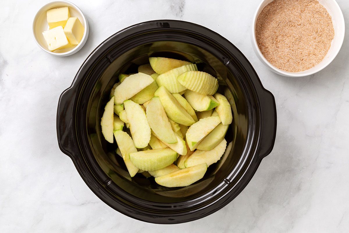 Chopped granny smith apples in a slow cooker for step two of Cinnamon Apples recipe for Taste of Home
