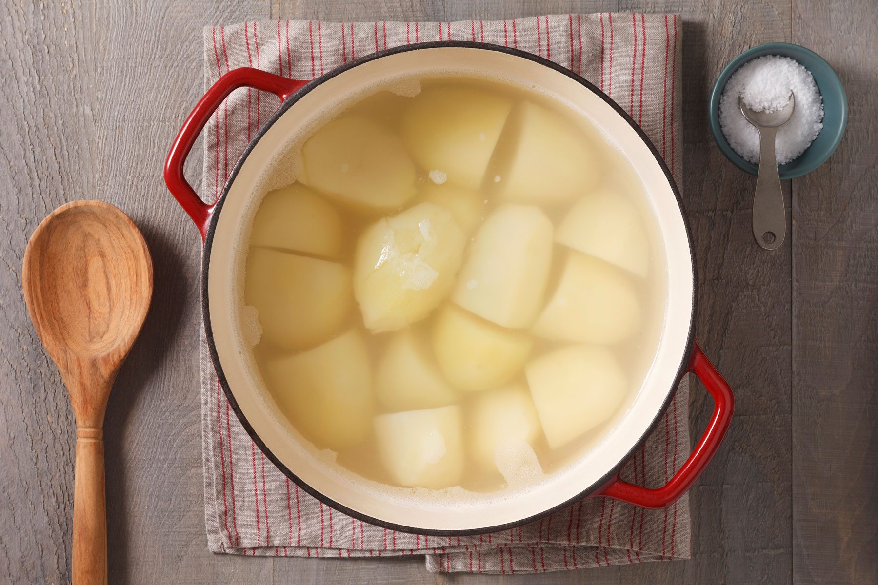 potatoes in water a stockpot with a small container of salt next to it.