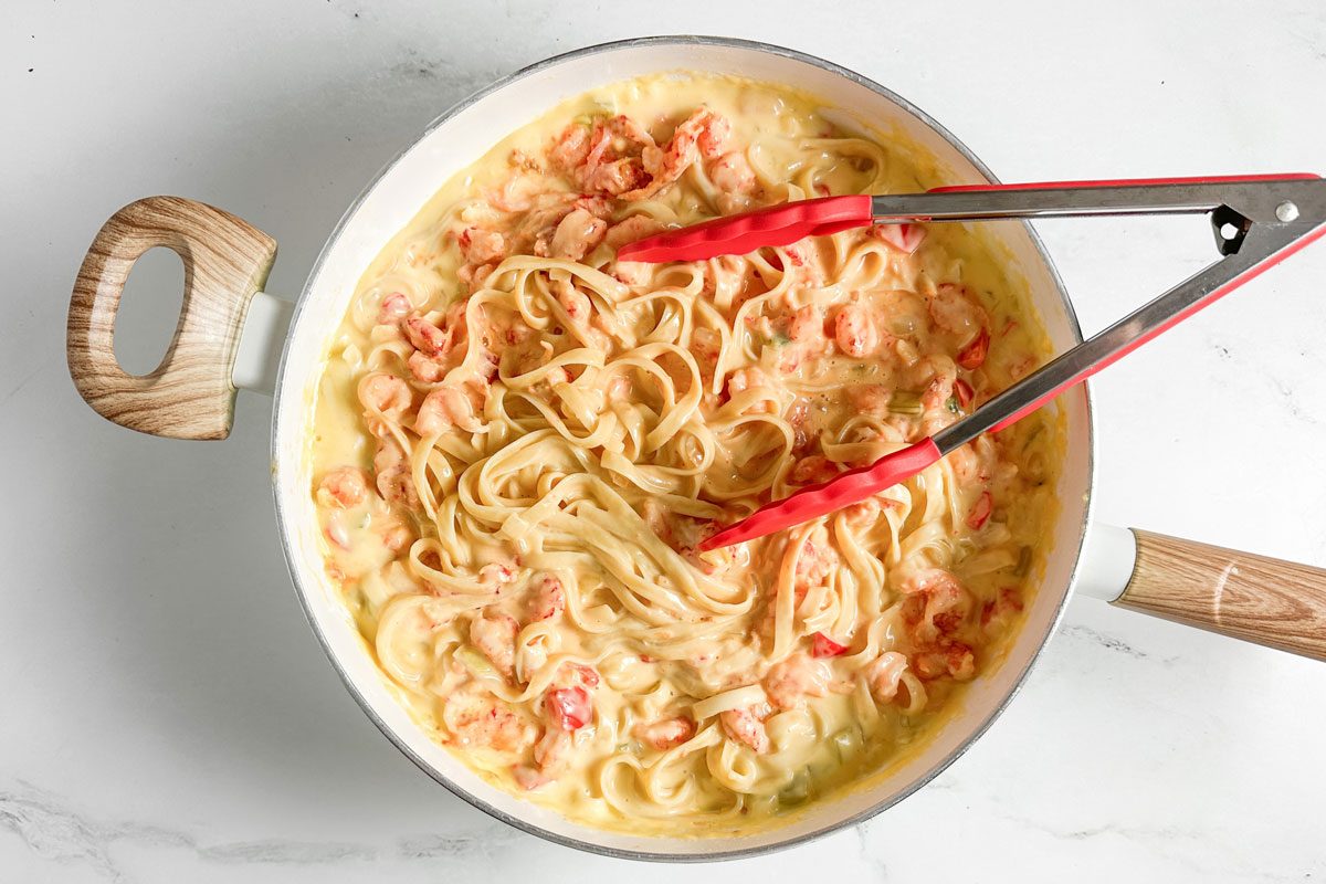 Taste of Home Crawfish Fettucine in a white skillet with kitchen tongs