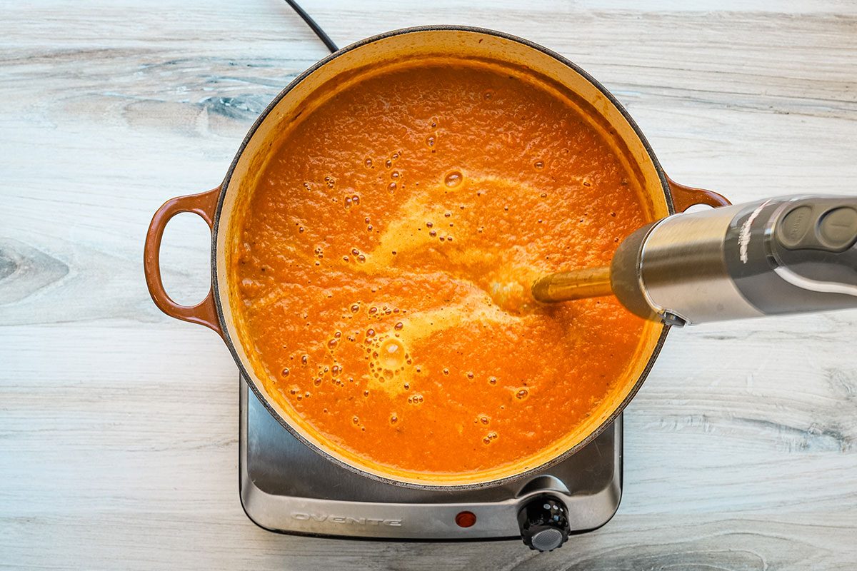 Blending carrot soup in a Dutch oven.