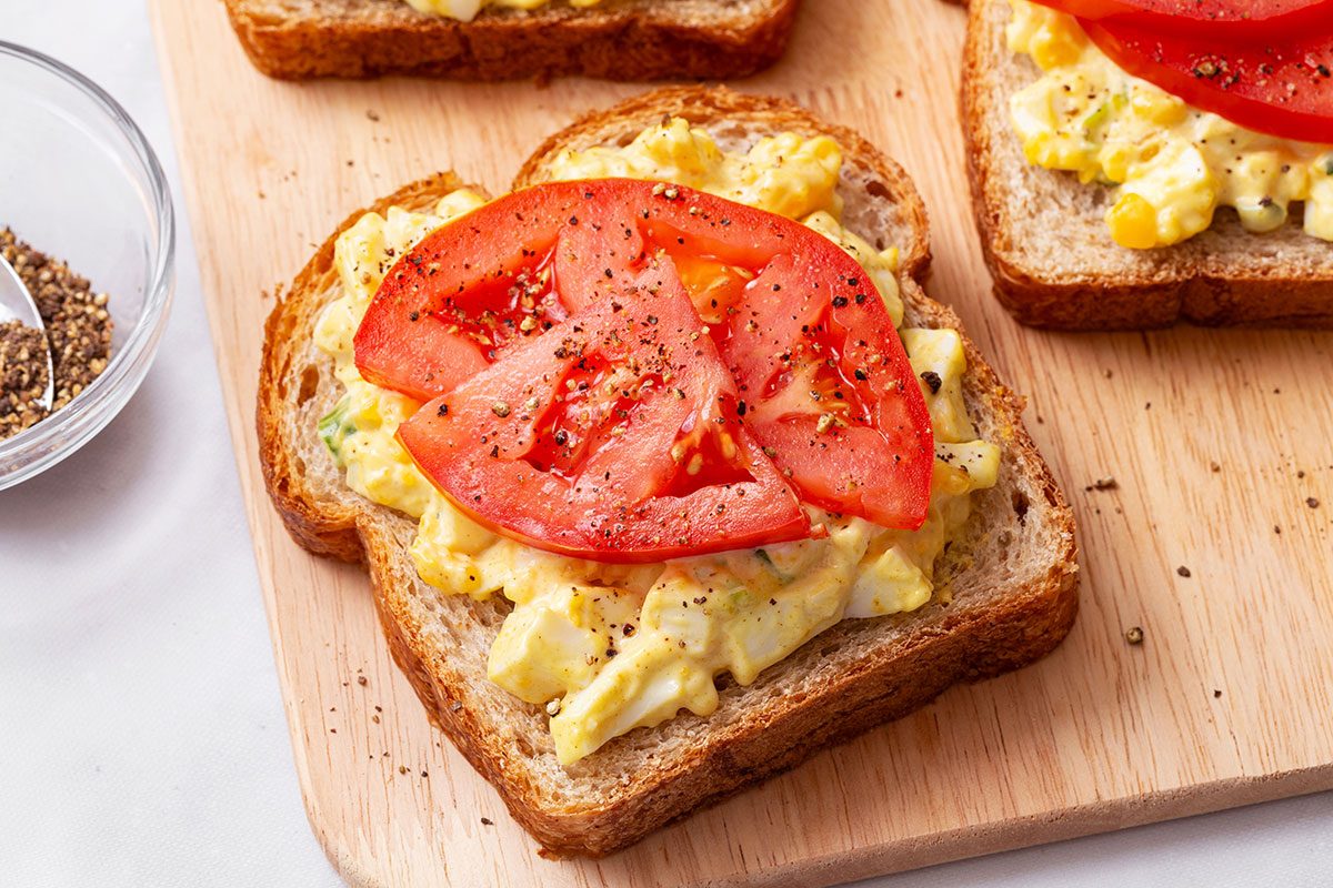 Whole wheat bread slice topped with Curried Egg Salad and seasoned tomato slices for Taste of Home