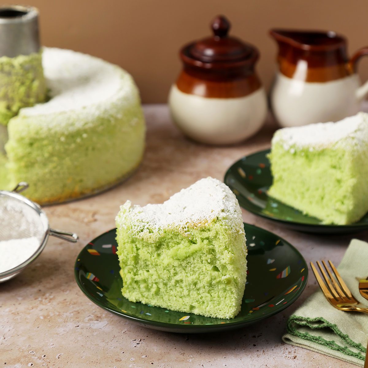 Close up of Taste of Home's Pandan Cake sliced and served on green plates on a brown marble surface.
