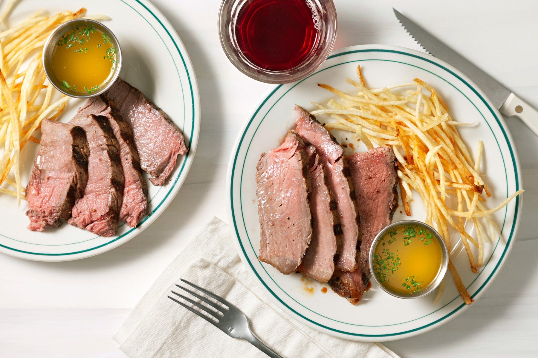 An overhead shot features a beautifully presented Florentine steak, accompanied by a generous dollop of herb garlic butter. The rich, grilled steak is garnished with fresh herbs, creating an appetizing and rustic display.