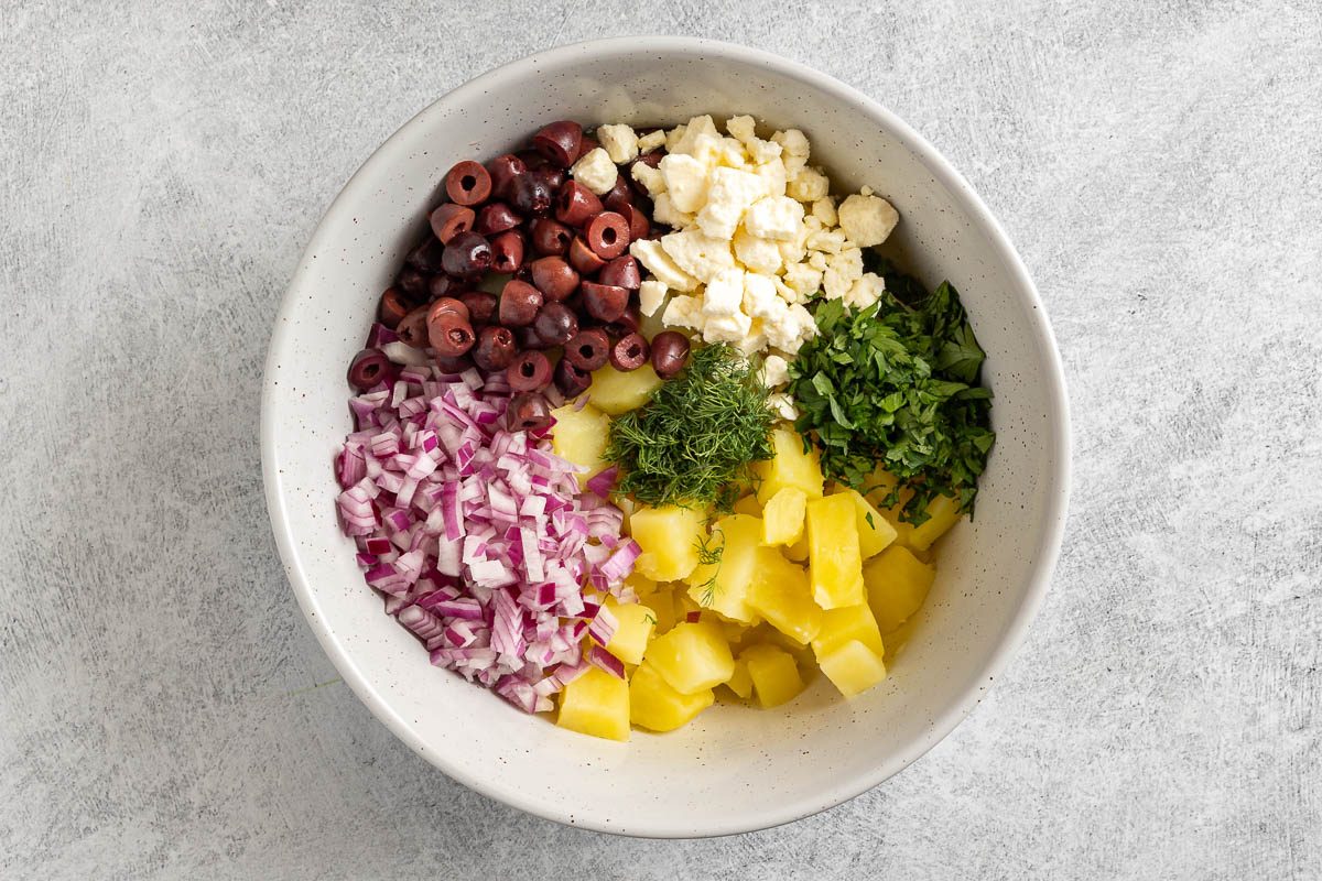 ingredients for greek potato salad in a bowl before mixing