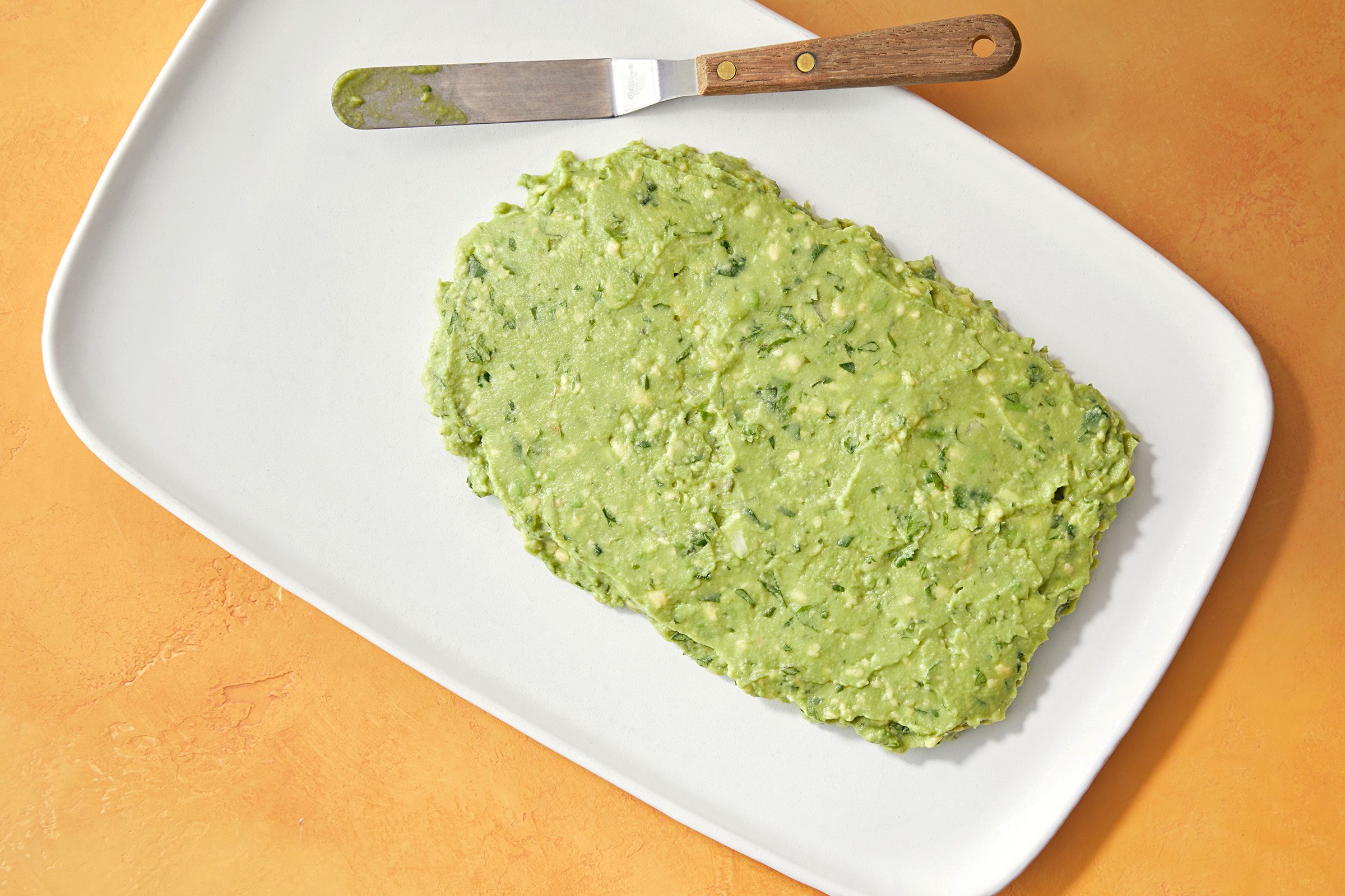 Guacamole smoothed and shaped into a rectangle on a white plate