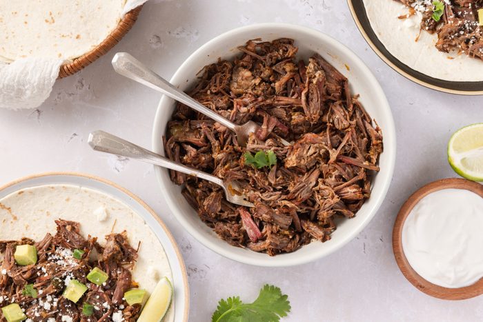 Instant pot beef carnitas shredded in bowl with forks ready to serve.