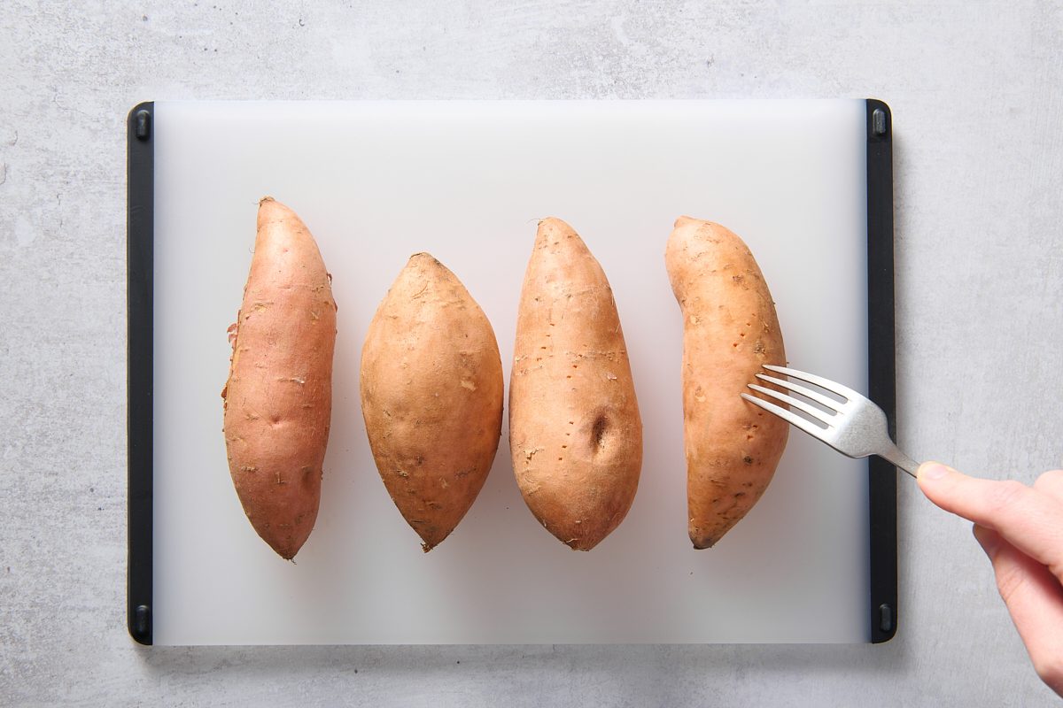 Piercing the sweet potatoes with a fork
