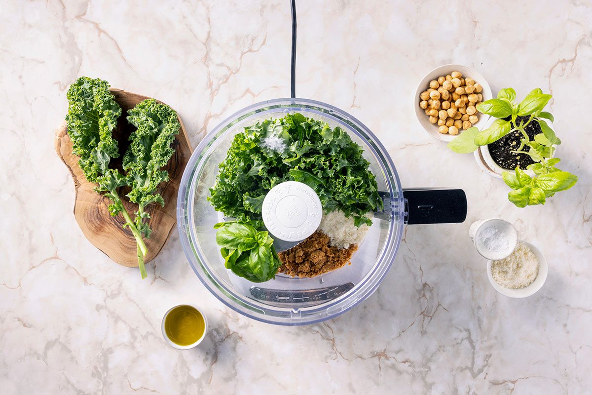 blending pesto ingredients in a food processor 