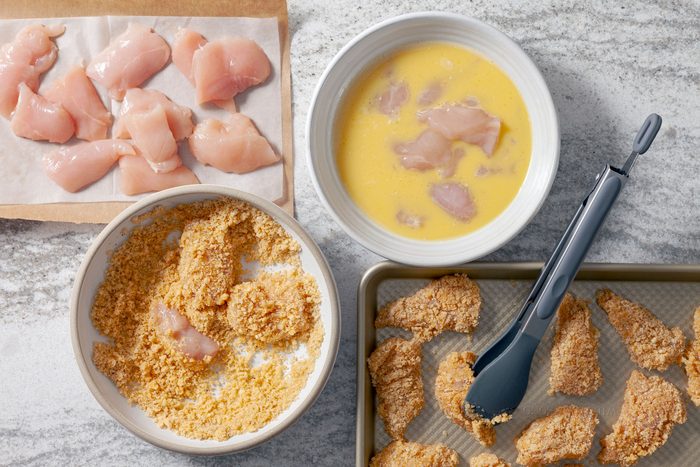 Chicken nuggets dipped in beaten eggs in one bowl. In another bowl they are dredged in keto breading mixture.