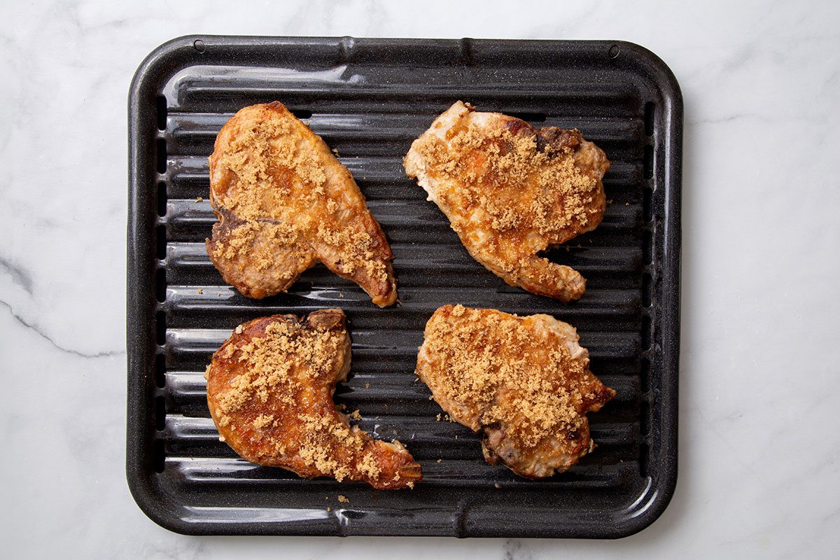 Pork chops sprinkled with brown sugar on a broiler pan for Maple-Glazed Pork Chops recipe for Taste of Home