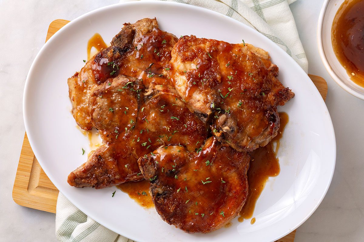 Overhead shot of Maple-Glazed Pork Chops on a serving platter sprinkled with parsley for Taste of Home