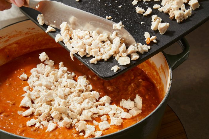 Adding chopped chicken to finish preparing Pappardelle Bolognese