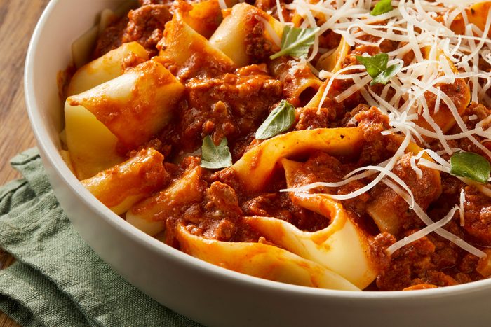 Close up shot of cheesy Pappardelle Bolognese in a big bowl