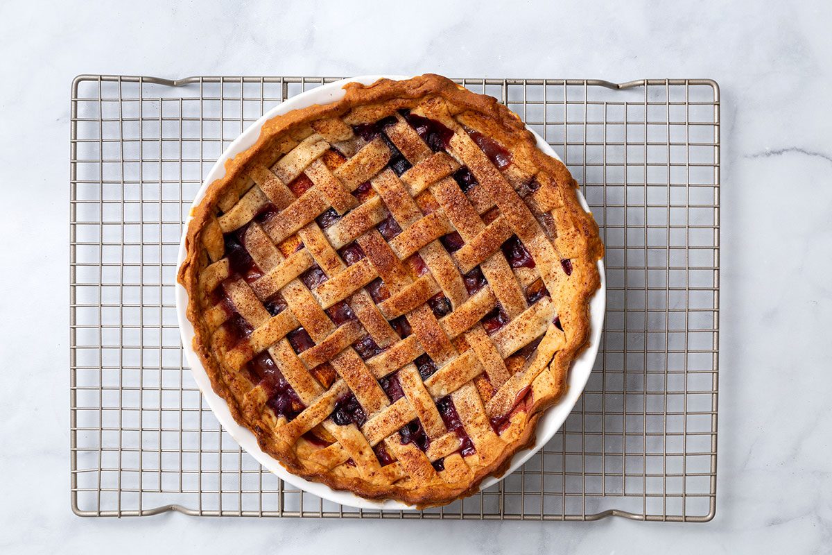 Baked peach and blueberry pie cooling on a wire rack for step five of Peach and Blueberry Pie for Taste of Home