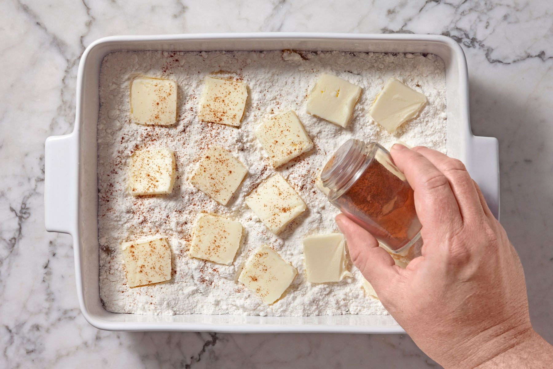 cinnamon being sprinkled over butter layer