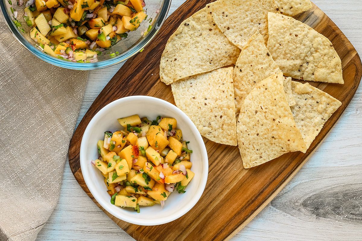Fresh peach salsa with tortilla chips for snacking.