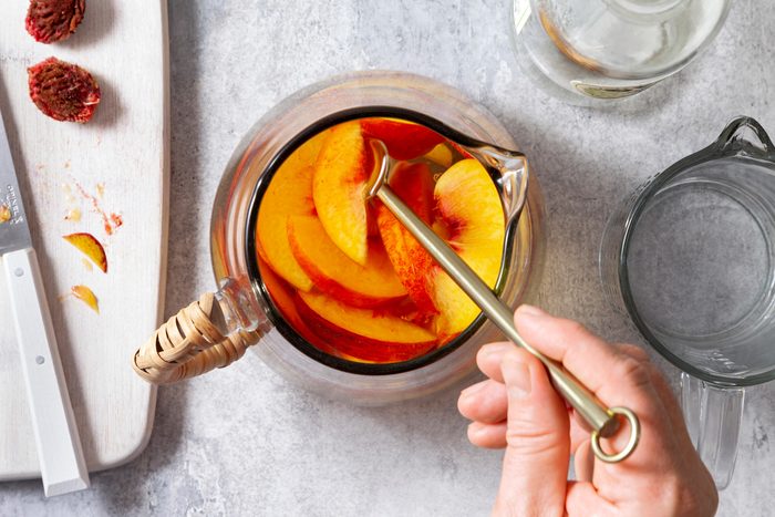 AN overhead shot of pitcher filled with peaches.