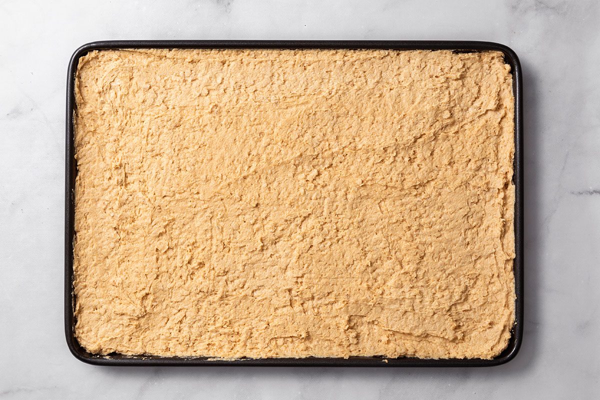 Bar mix spread into a greased 15x10x1-inch baking pan for step two of Peanut Butter Cookie Bars for Taste of Home