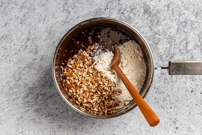 adding the flour and pecans to the sauce pan.