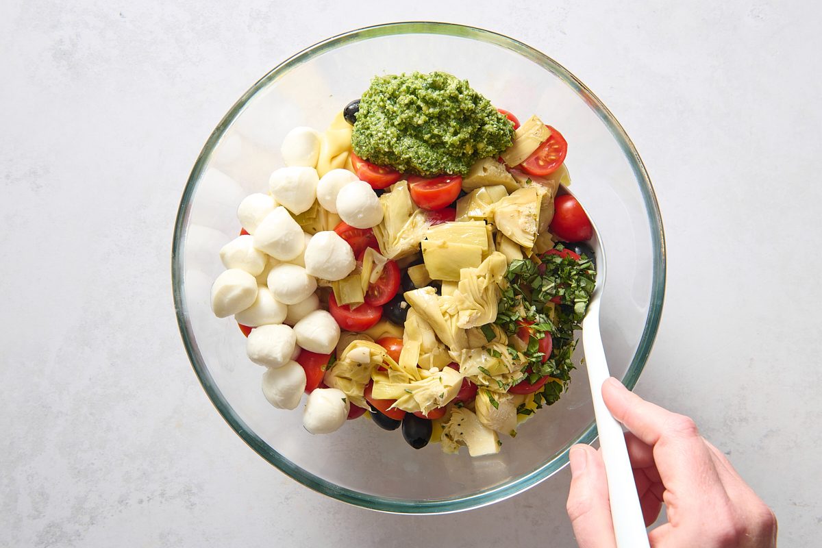 Combining the tortellini salad ingredients in a large bowl