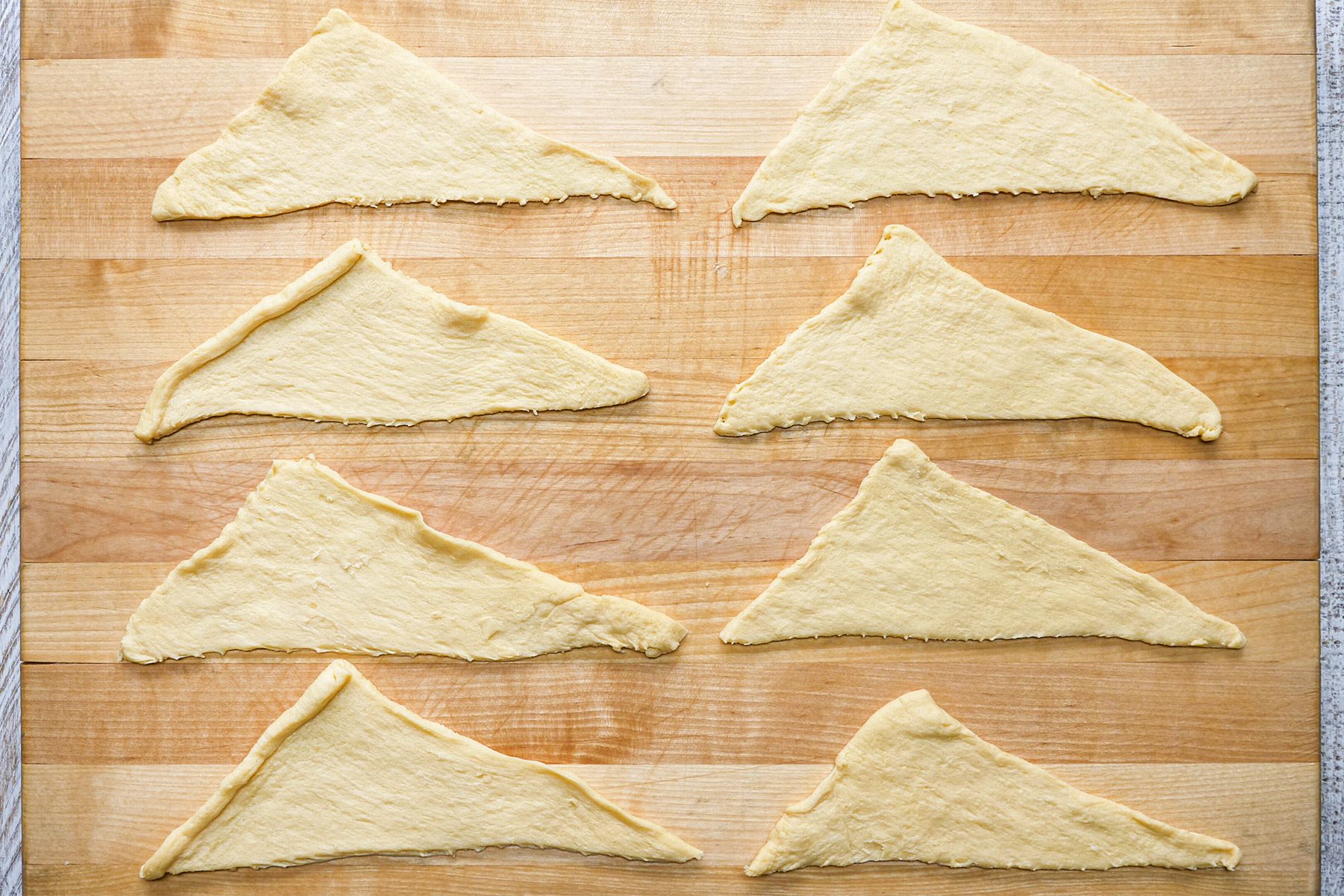 overhead shot; white wooden textured background; Separate crescent dough into triangle; over wooden board;