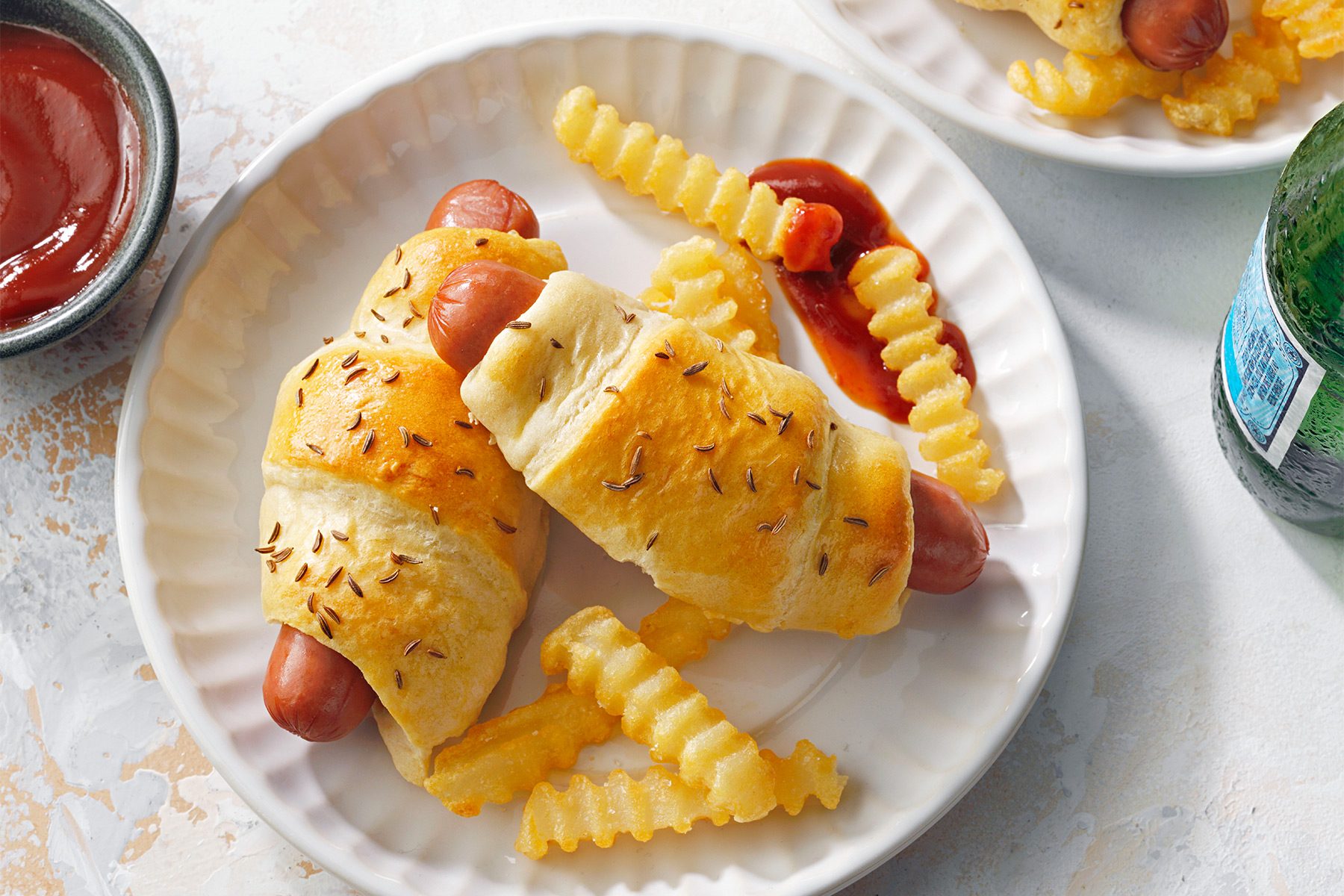 wide shot of pigs in a blanket served with fries and ketchup