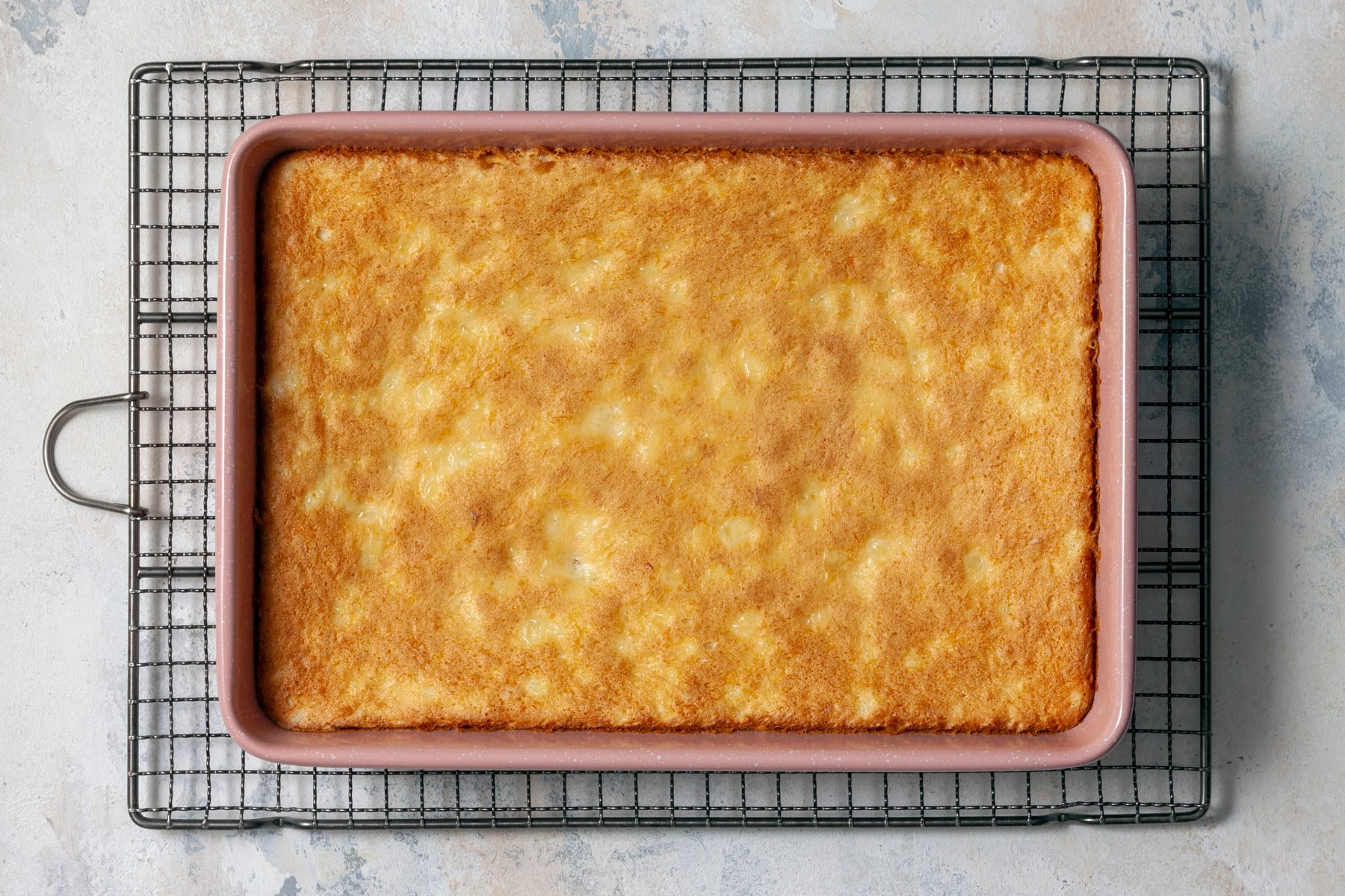 A baked cake sits in a baking dish, golden brown and ready to be served.