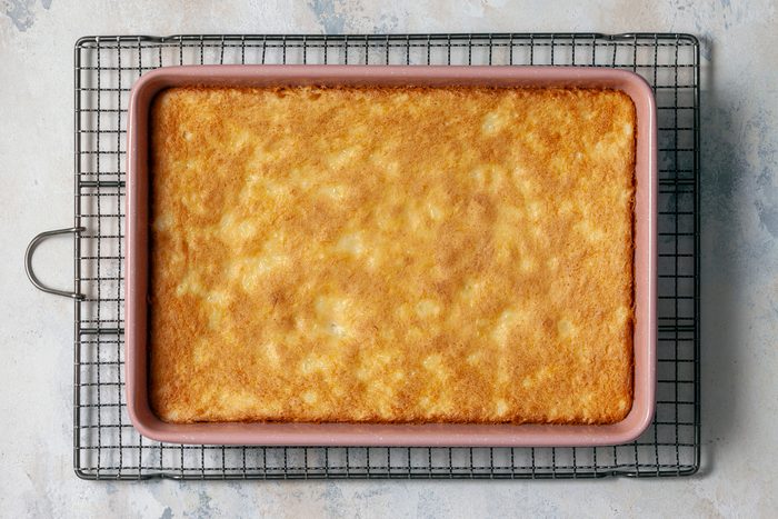 A baked cake sits in a baking dish, golden brown and ready to be served.