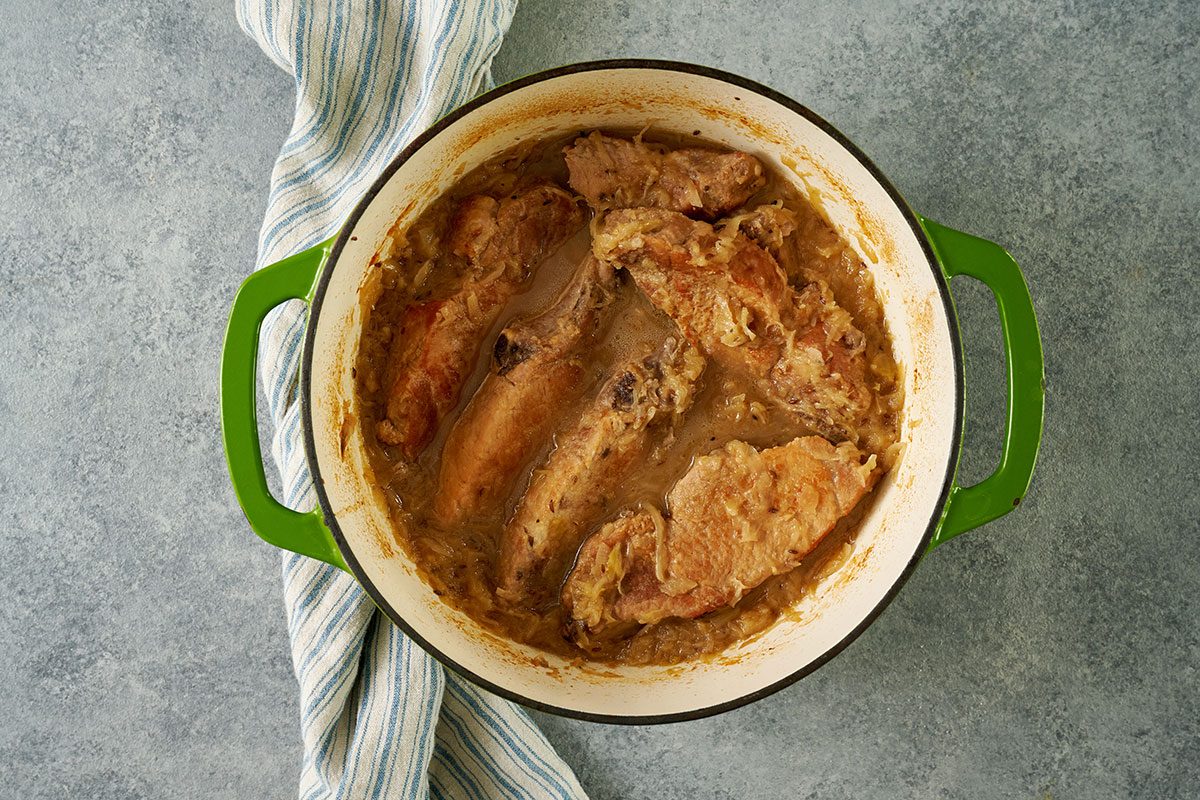 Overhead view of the pork ribs and sauerkraut mixture in a Dutch oven, baked in the oven for the Taste of Home Pork and Sauerkraut recipe.