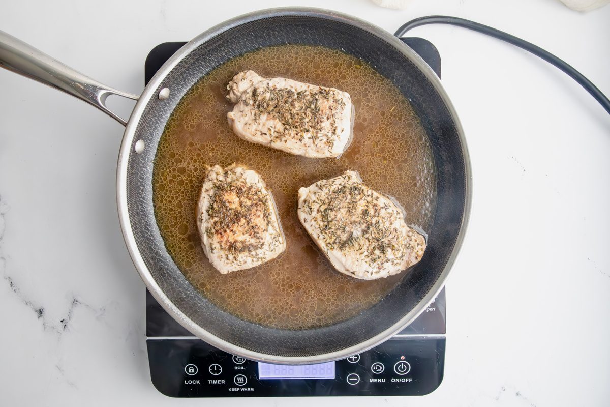 Overhead shot for Taste of Home Pork Chops and Noodles, pork chops cooking over an induction stovetop.