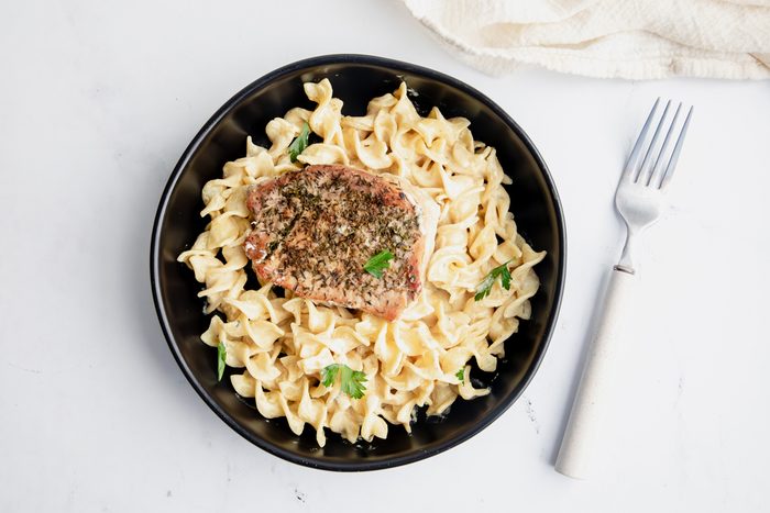 Overhead beauty shot for Taste of Home Pork Chops and Noodles, being served in a black bowl.