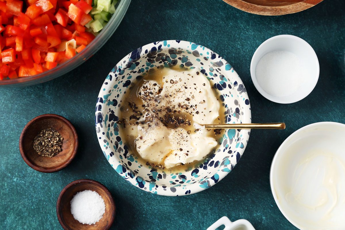 Process of making Taste of Home's Creamy Pasta Salad in a large mixing bowl on a green surface.