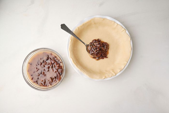 Rolling out the pie dough and adding the raisin filling to a 9-inch pie shell. Taste of Home Raisin Pie recipe.