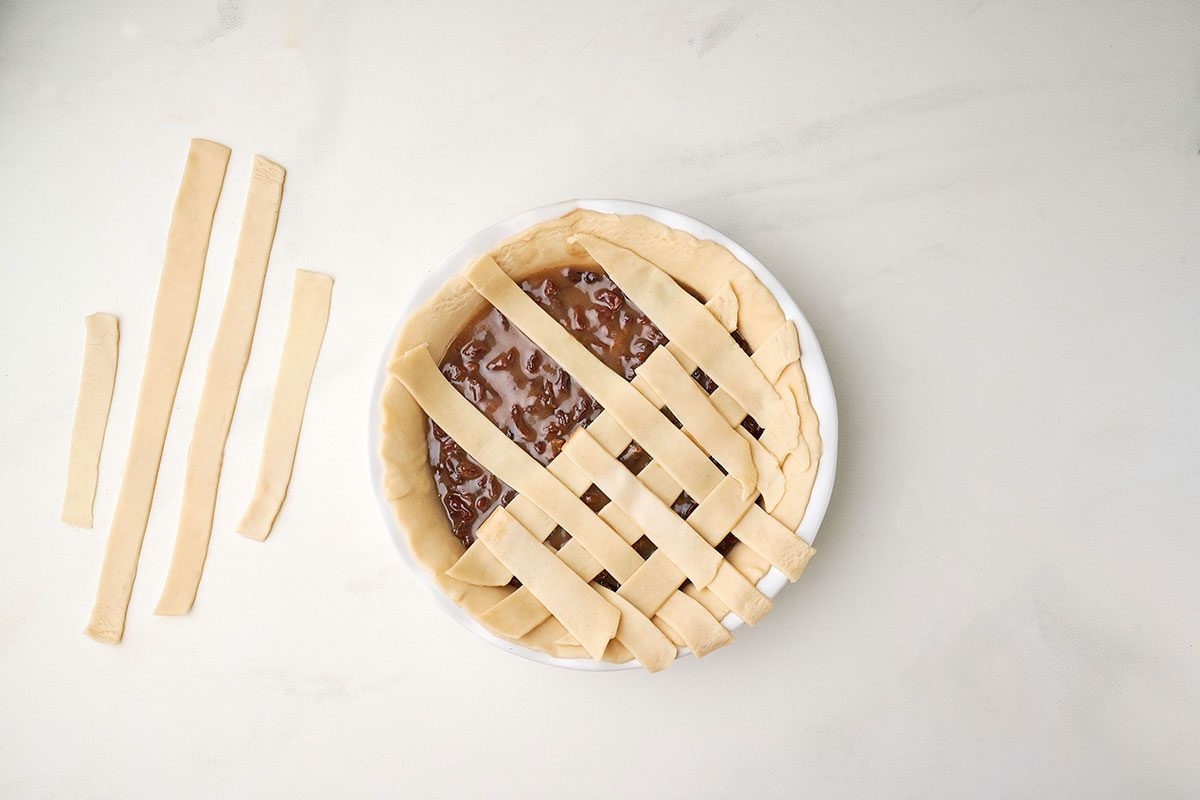 Creating a lattice pie crust for Taste of Home's Raisin Pie recipe, trimming the edges to seal the filling.
