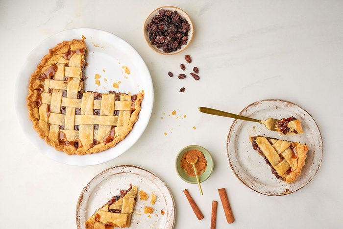 Taste of Home's Raisin Pie recipe, featuring a fully baked pie with a golden-brown lattice crust, placed on a light white surface.